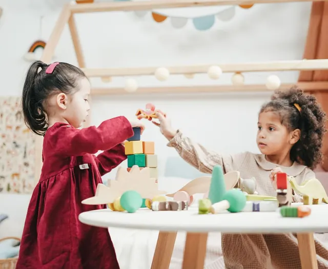 Two children playing with wooden blocks at a round table