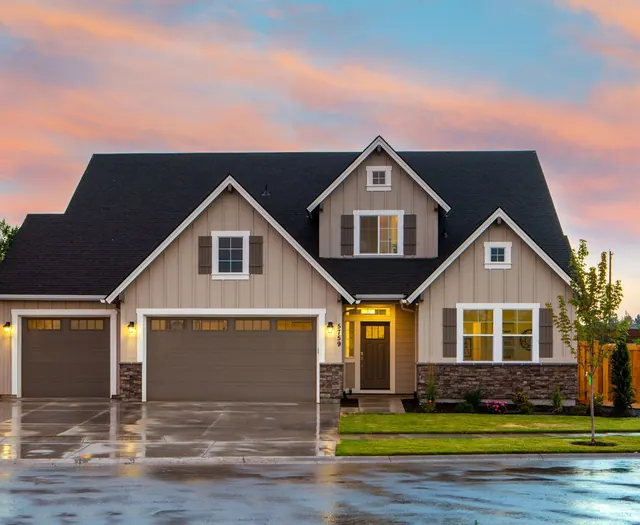 A suburban home at dusk with warm porch lights