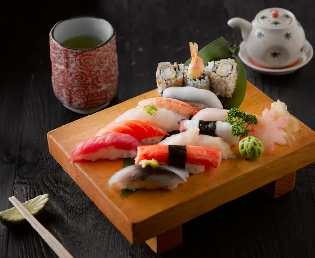 A wooden geta of nigiri and rolls with green tea